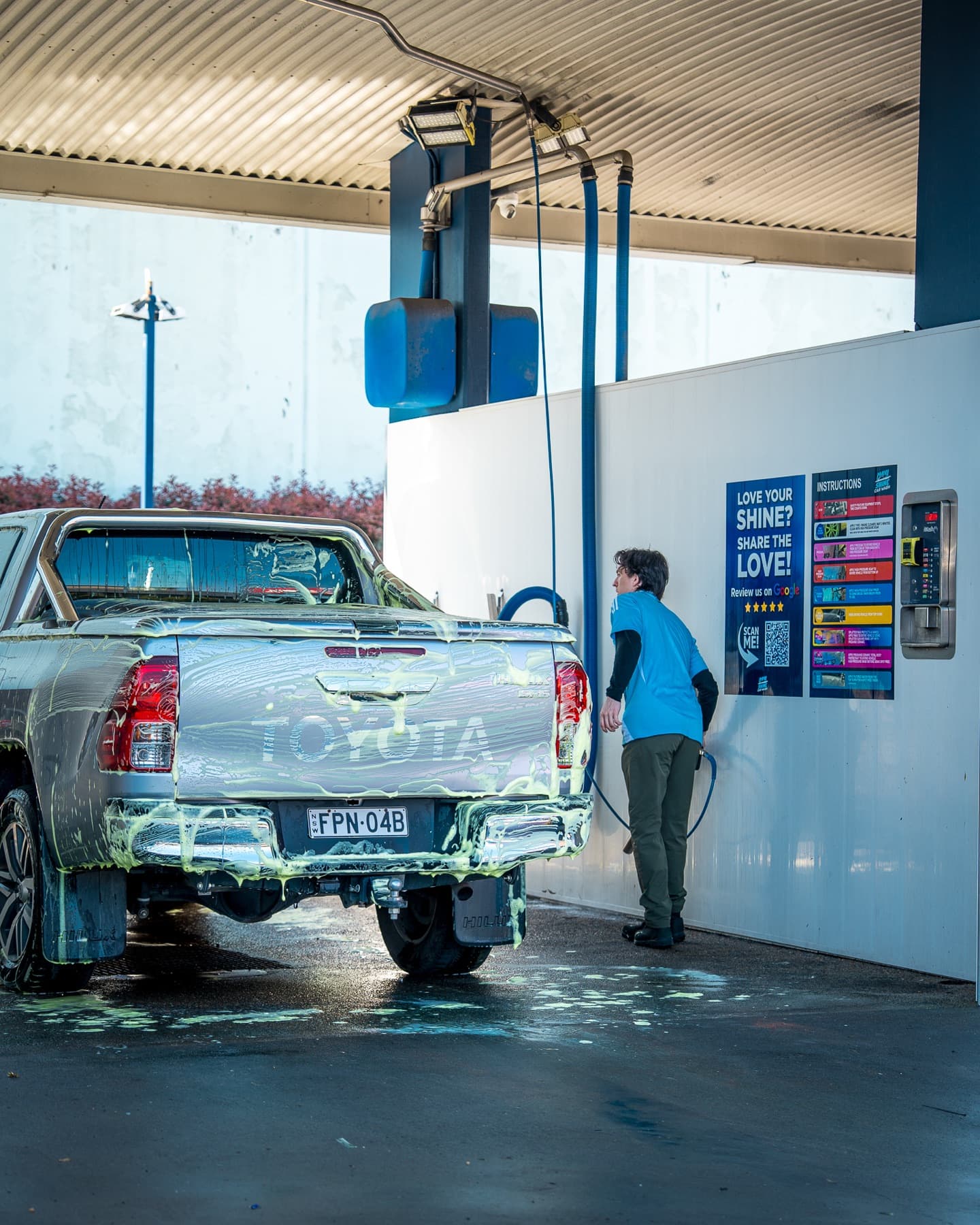 A silver Toyota Hilux covered in foam at a Maxishine self-service bay