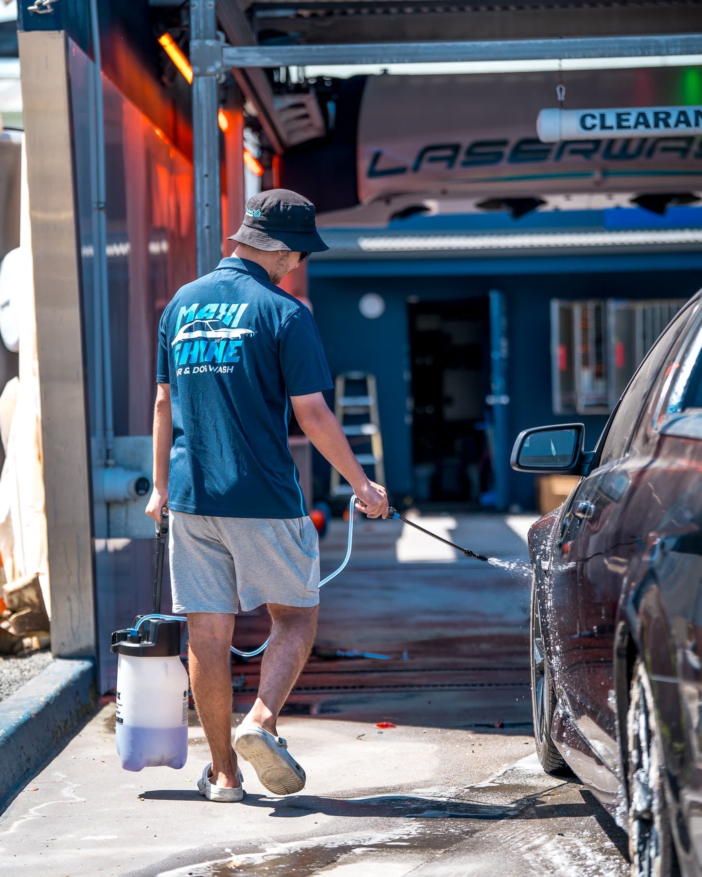 A Maxishine team member pressure washing a car during staffed hours